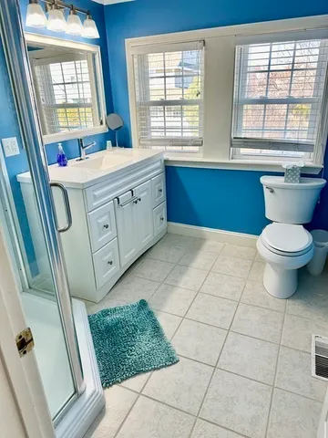 a bathroom with a sink a toilet a mirror a window and vanity