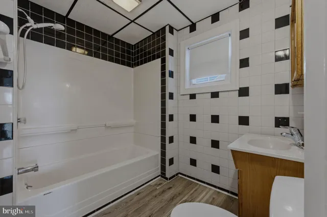 a bathroom with a bathtub shower sink mirror and toilet