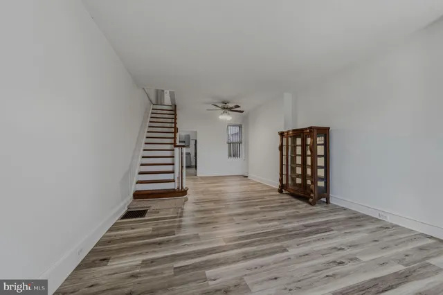 a view of an empty room with wooden floor and stairs