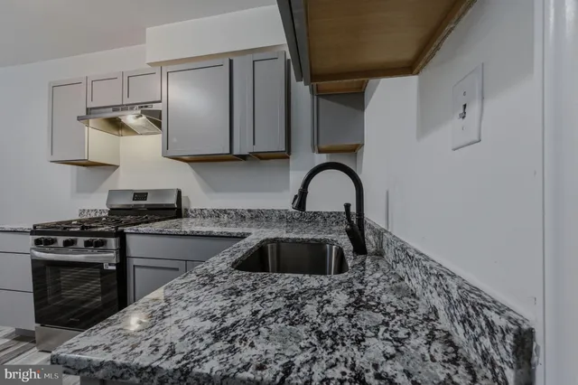 a kitchen with granite countertop a stove sink and cabinets