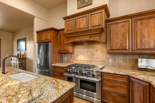 a kitchen with stainless steel appliances granite countertop a stove a sink and a refrigerator