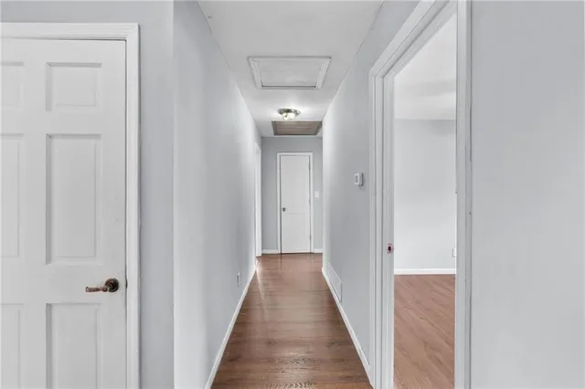 a view of an empty room with window and wooden floor