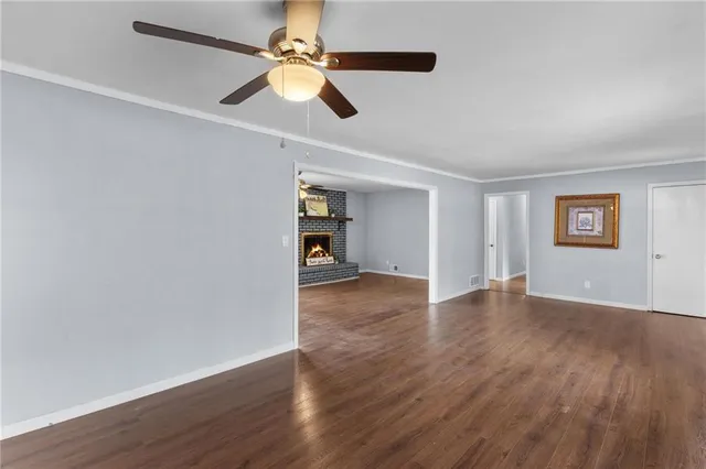 a view of an empty room with window and wooden floor