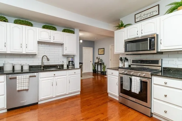 a kitchen with stainless steel appliances granite countertop a stove a sink and a microwave