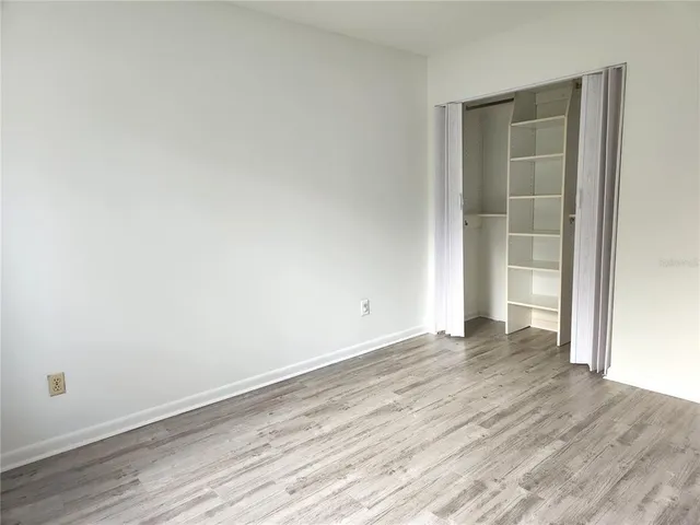 an empty room with wooden floor and closet