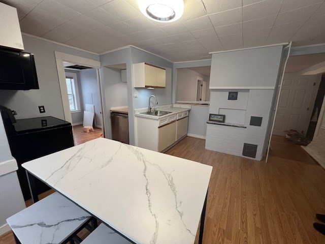 a kitchen with a sink a stove wooden floor and black appliances
