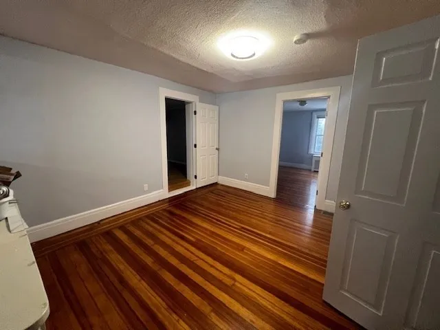 a view of an empty room with wooden floor and closet