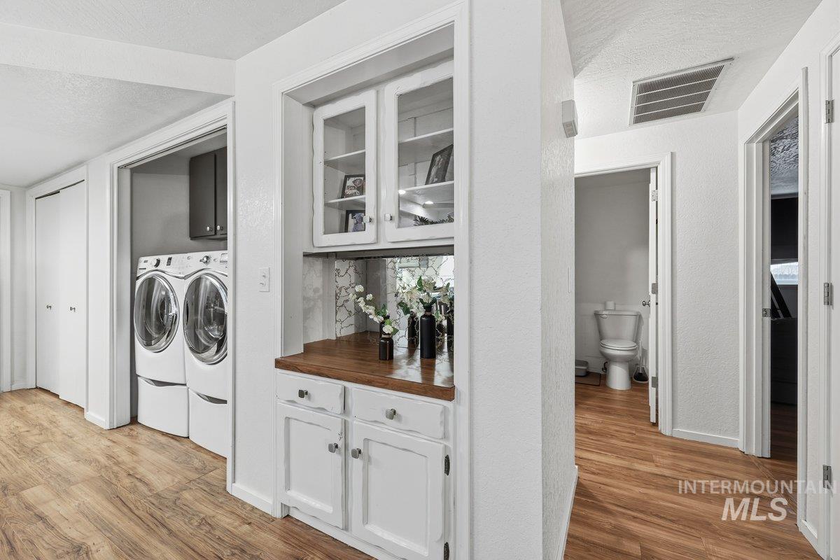 2920 South 10th Avenue Caldwell, ID 83605 - Photo 16 of 21 Laundry area featuring light wood-type flooring, a textured ceiling, washing machine and clothes dryer, and cabinet space