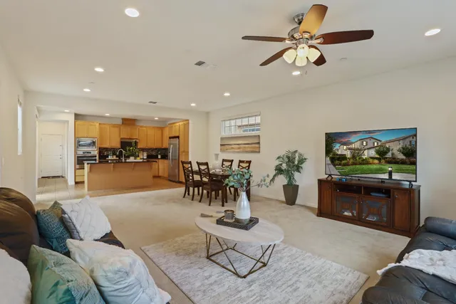 a living room with furniture kitchen view and a chandelier