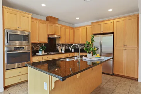 a kitchen with stainless steel appliances granite countertop a sink a stove and a refrigerator