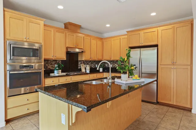 a kitchen with stainless steel appliances granite countertop a sink a stove and a refrigerator