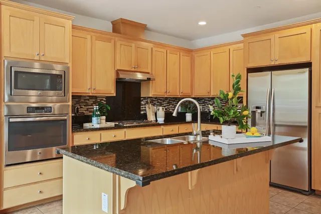 a kitchen with granite countertop a sink a counter top space appliances and cabinets