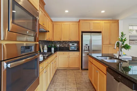 a kitchen with stainless steel appliances granite countertop a sink a stove and a refrigerator