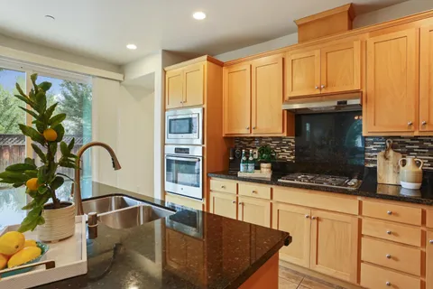 a kitchen with stainless steel appliances granite countertop a stove a sink and a microwave
