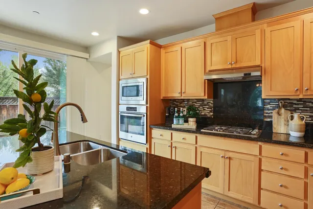 a kitchen with stainless steel appliances granite countertop a stove a sink and a microwave