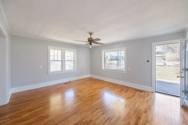 a view of an empty room with wooden floor and a window