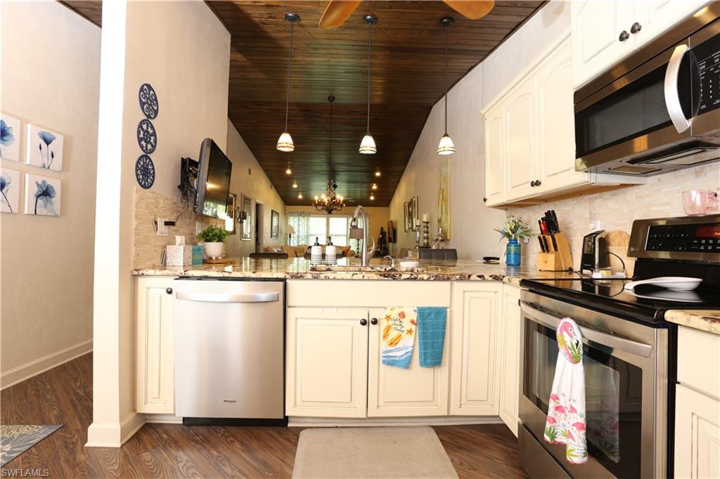 3563 Antarctic Circle, Unit 2102 Naples, FL 34112 - Photo 8 of 26 a kitchen with stainless steel appliances granite countertop a stove a sink and a microwave
