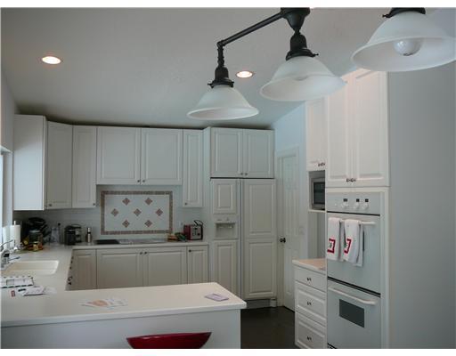 7149 Encina Lane Boca Raton, FL 33433 - Photo 3 of 22 a kitchen with kitchen island white cabinets and refrigerator
