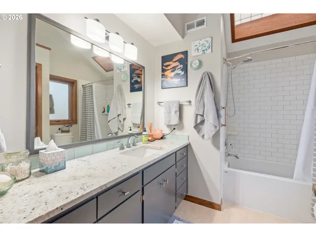 a bathroom with a granite countertop sink mirror vanity and bathtub