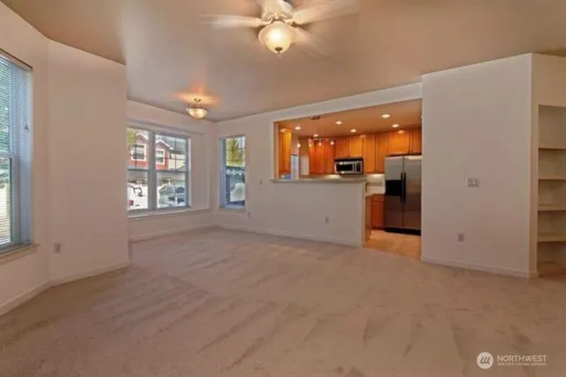 an empty room with windows and ceiling fan