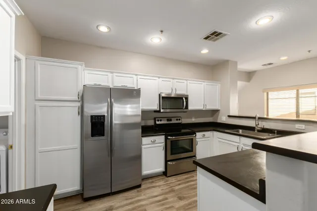 a kitchen with stainless steel appliances granite countertop a sink a stove and a refrigerator