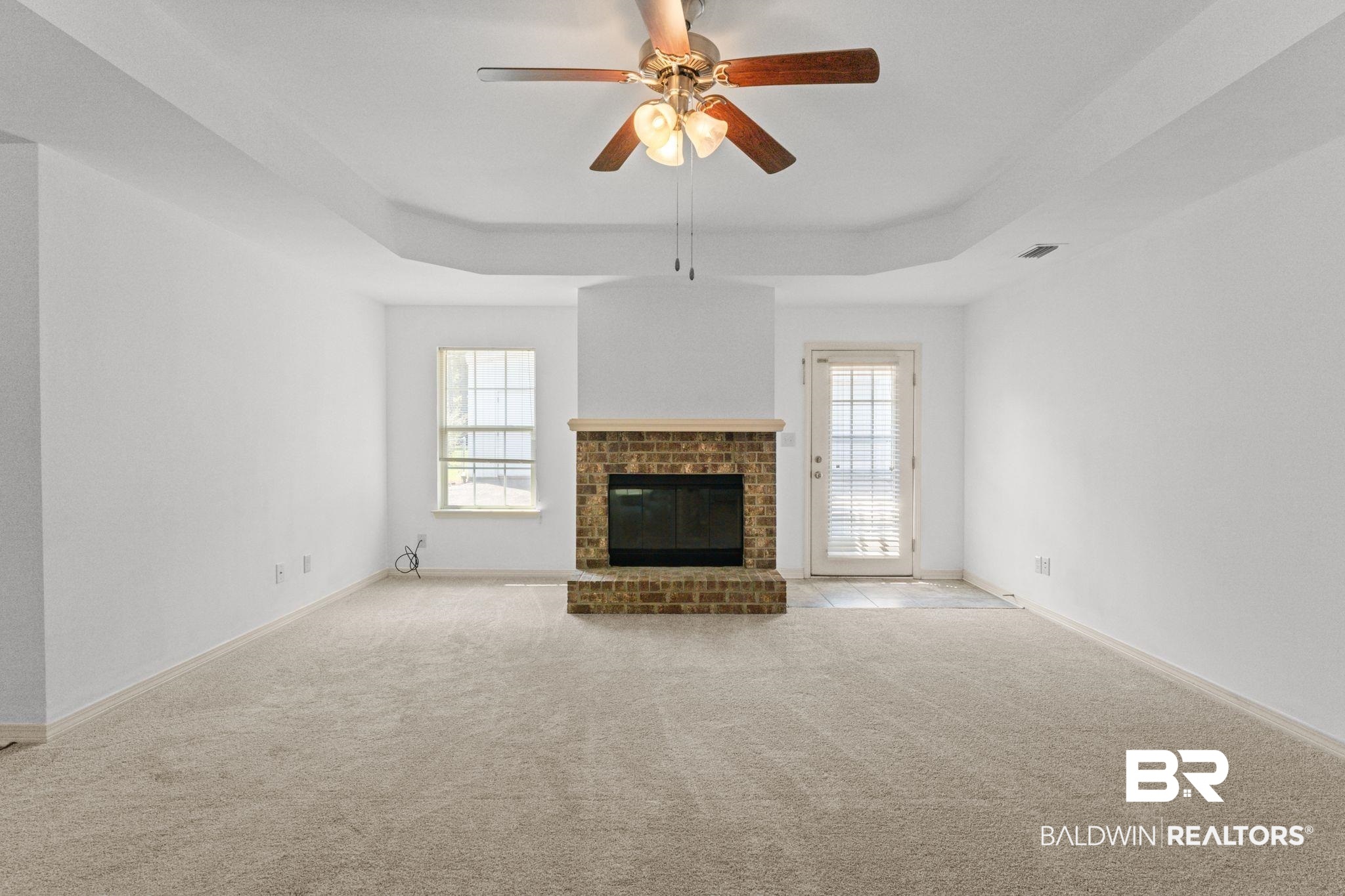 10535 Rhett McConnell Road Theodore, AL 36582 - Photo 11 of 36 Unfurnished living room with a raised ceiling, carpet floors, a fireplace, and a ceiling fan