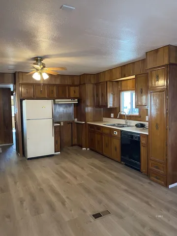 a kitchen with stainless steel appliances a refrigerator a sink cabinets and wooden floor