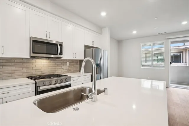 a kitchen with stainless steel appliances granite countertop a sink and a stove top oven with wooden floor