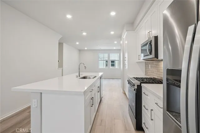 a kitchen with stainless steel appliances granite countertop a refrigerator a stove and a sink