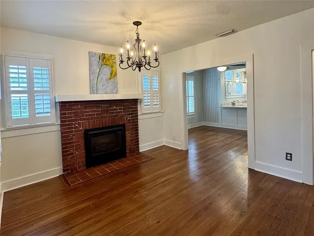 a view of a livingroom with a fireplace wooden floor and a window