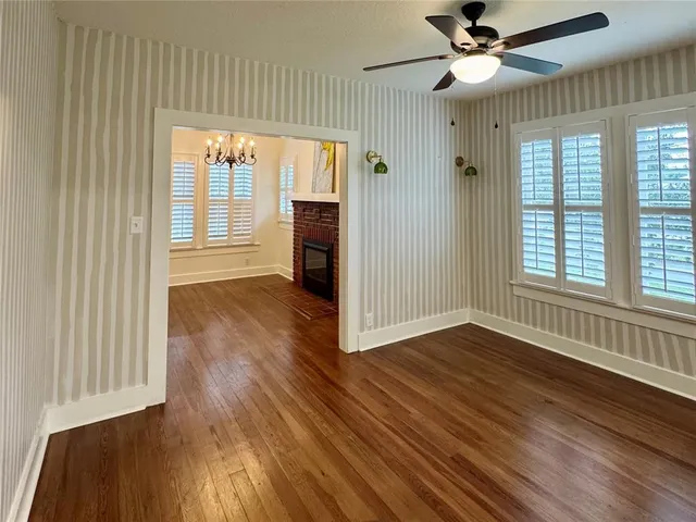 an empty room with wooden floor fan and windows