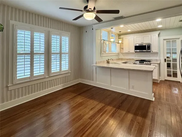 a view of a kitchen with stainless steel appliances wooden floor and a large window