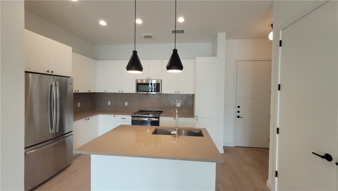 800 Embassy Drive, Unit 429 Austin, TX 78702 - Photo 1 of 39 a kitchen with stainless steel appliances granite countertop a refrigerator a sink dishwasher a stove and a refrigerator with wooden floor