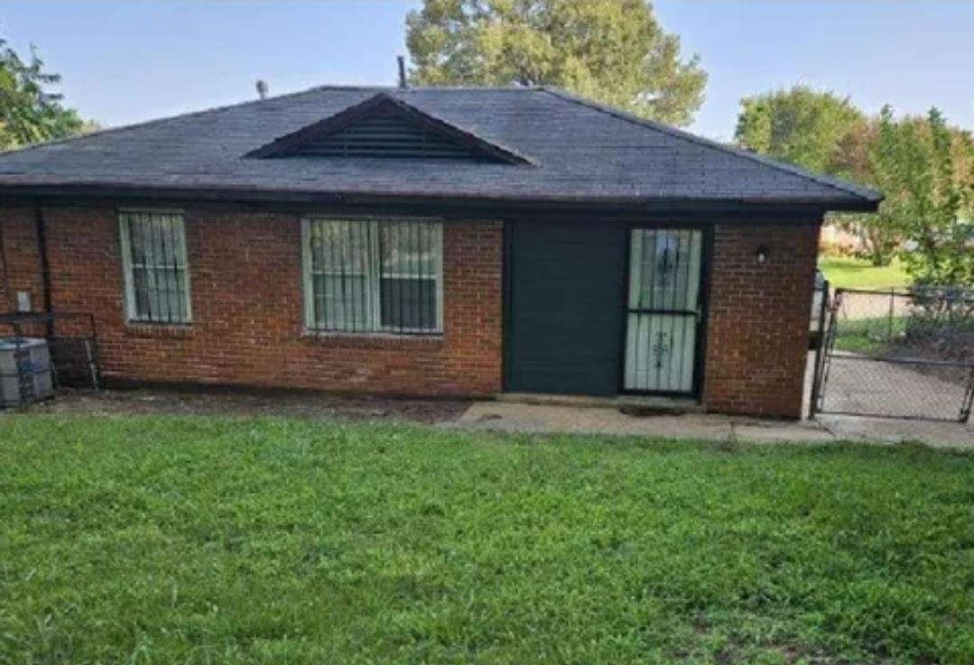 3497 Brantley Road Memphis, TN 38109 - Photo 2 of 10 Rear view of house featuring central AC unit, fence, a lawn, and brick siding