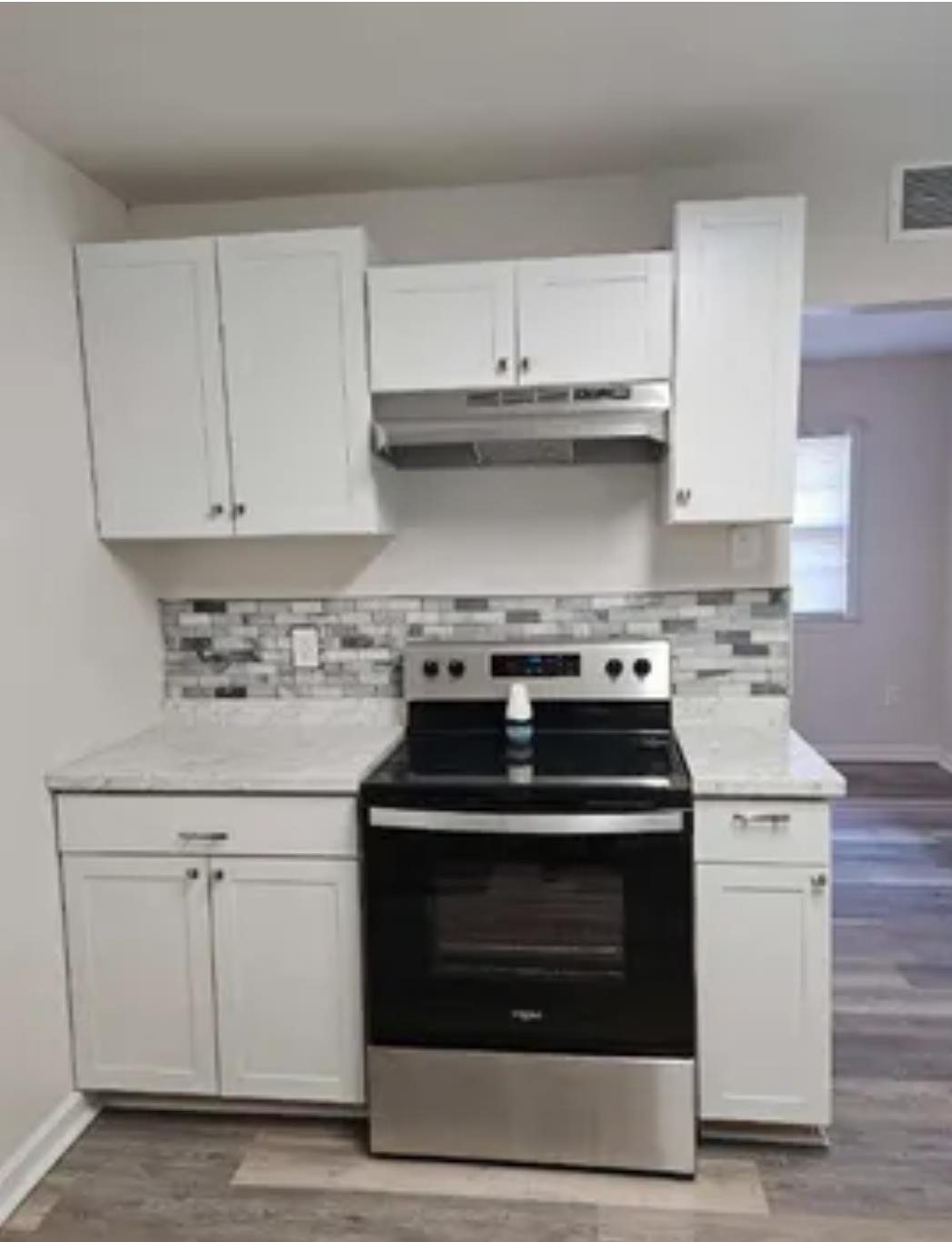 3497 Brantley Road Memphis, TN 38109 - Photo 3 of 10 Kitchen featuring light countertops, electric stove, white cabinets, and under cabinet range hood