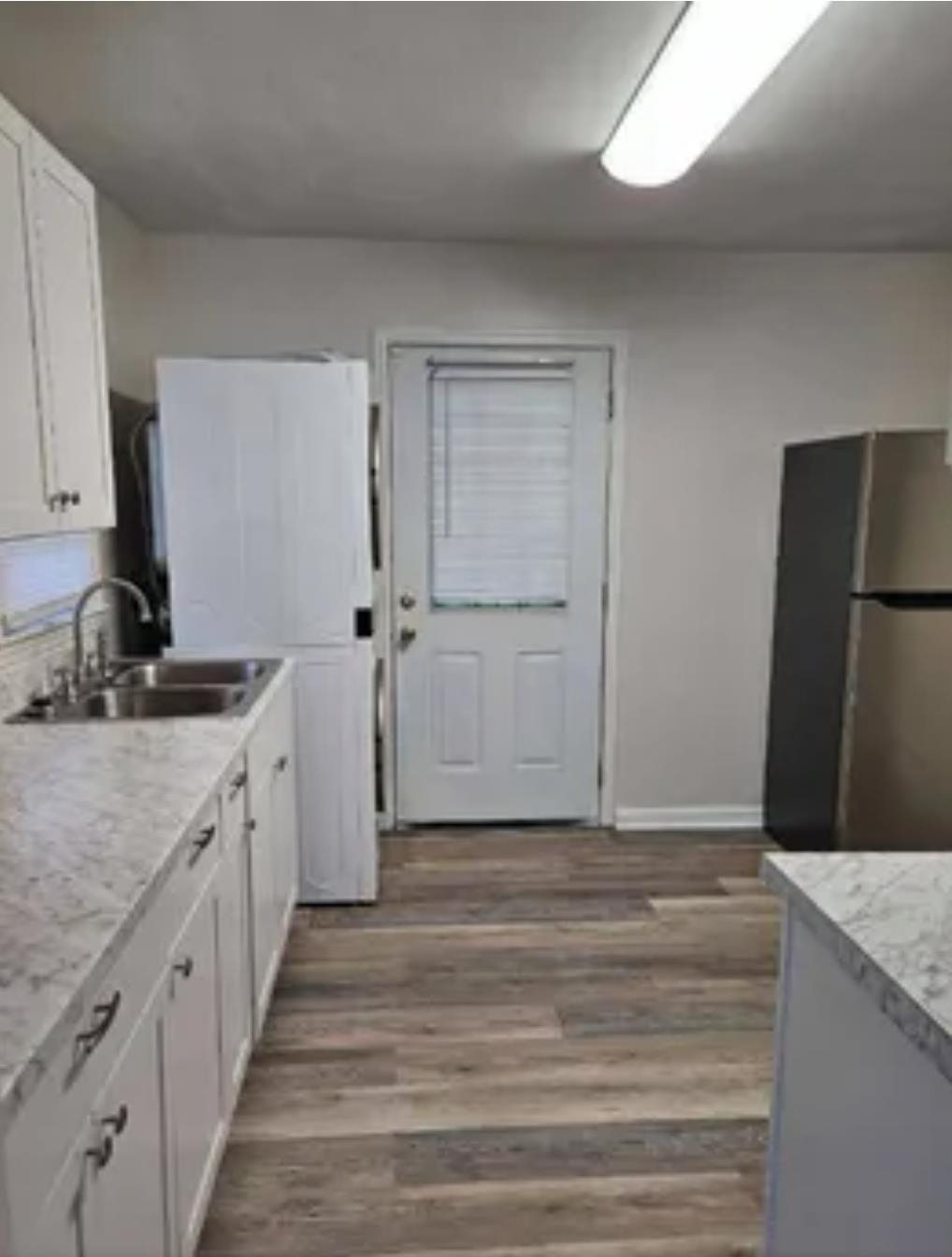 3497 Brantley Road Memphis, TN 38109 - Photo 5 of 10 Kitchen featuring baseboards, dark wood finished floors, white cabinets, freestanding refrigerator, and a sink