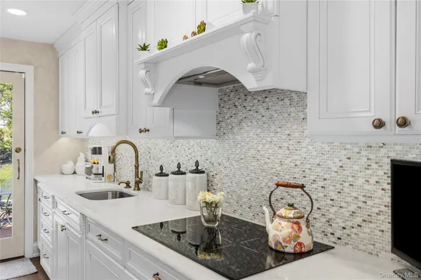 a kitchen with stainless steel appliances a sink a stove and white cabinets