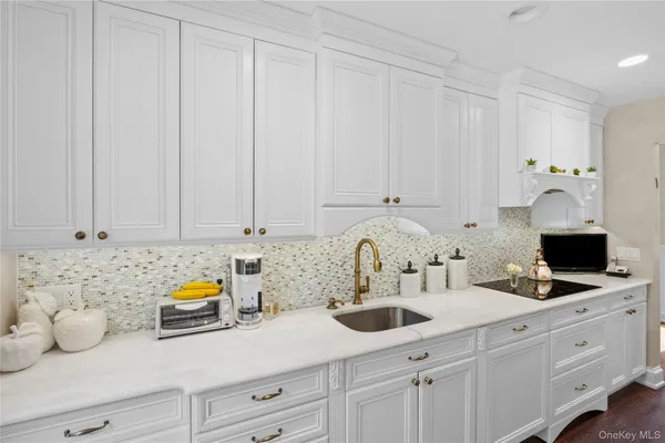 a kitchen with white cabinets and sink
