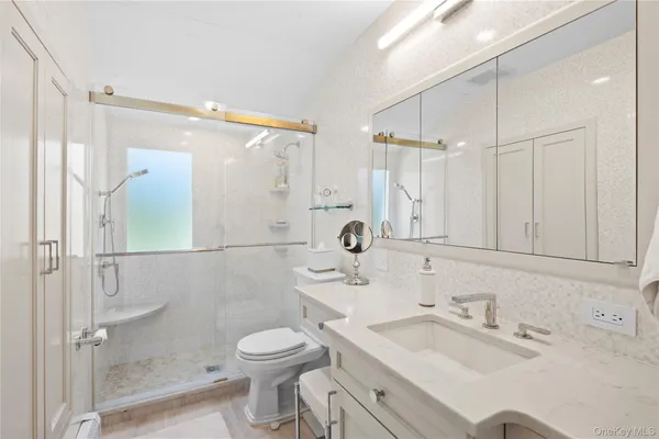 a bathroom with a sink vanity granite toilet and shower