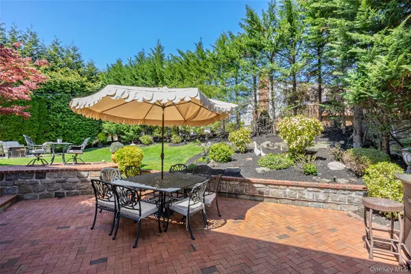 a view of patio with chairs and a table and chairs under an umbrella with potted plants