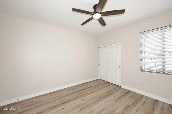 an empty room with wooden floor ceiling fan and windows