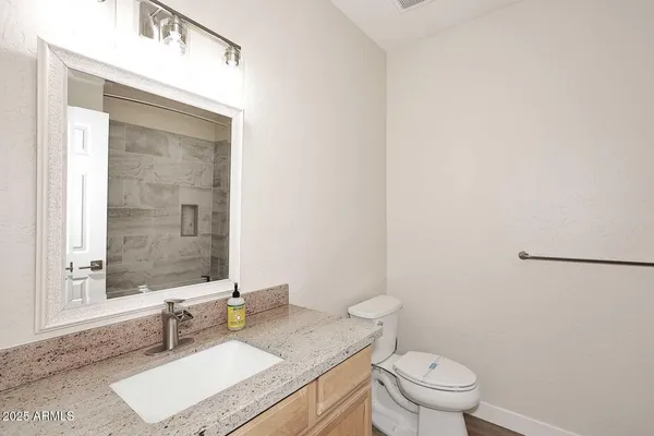 a bathroom with a granite countertop sink a mirror and a toilet