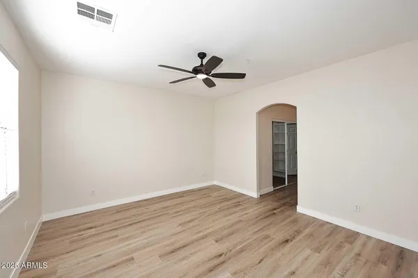 an empty room with wooden floor ceiling fan and window