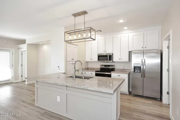 a kitchen with kitchen island granite countertop a sink appliances cabinets and wooden floor