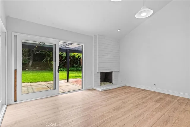 a view of an empty room with wooden floor and a fireplace