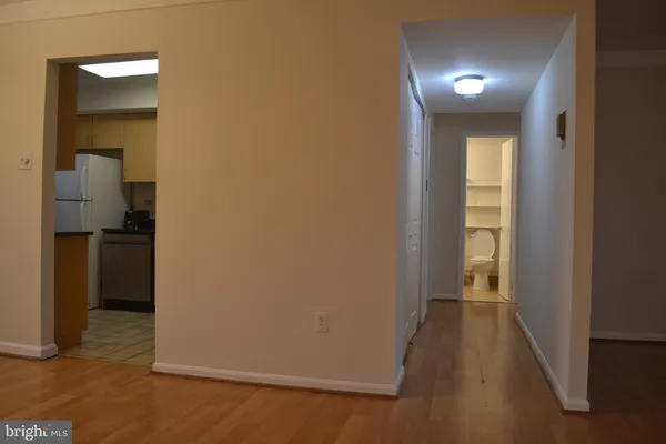 a view of a hallway with wooden floor and a living room