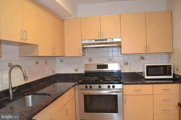 a kitchen with stainless steel appliances granite countertop a stove a sink and white cabinets