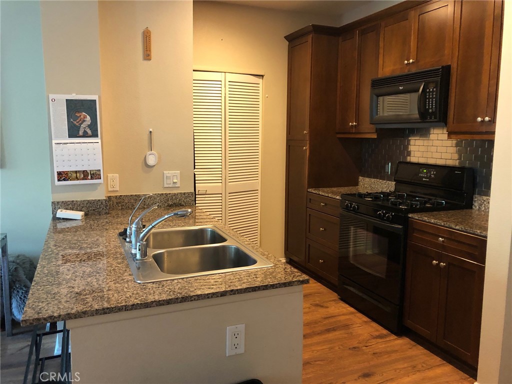 2377 Scholarship Irvine, CA 92612 - Photo 11 of 37 a kitchen with granite countertop a sink and a stove top oven with wooden floor