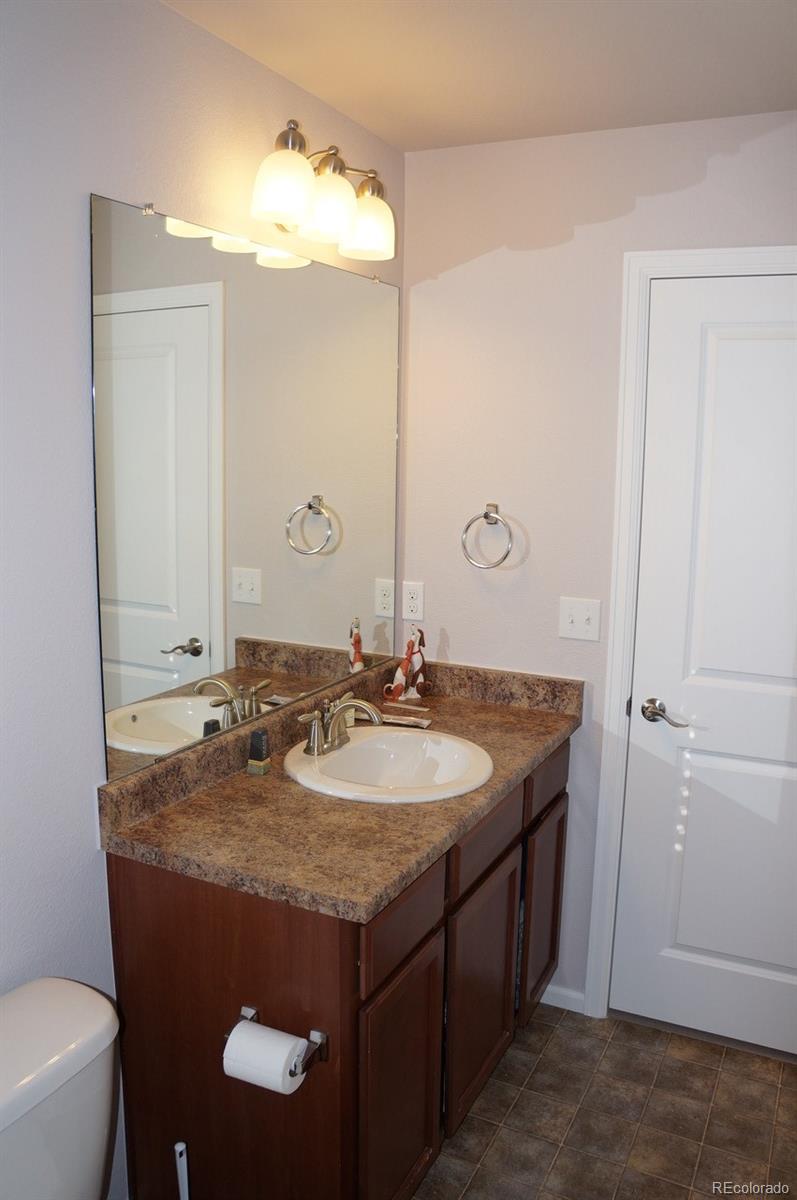 10269 Bellwether Lane Lone Tree, CO 80124 - Photo 13 of 17 a bathroom with a granite countertop sink a toilet and a mirror