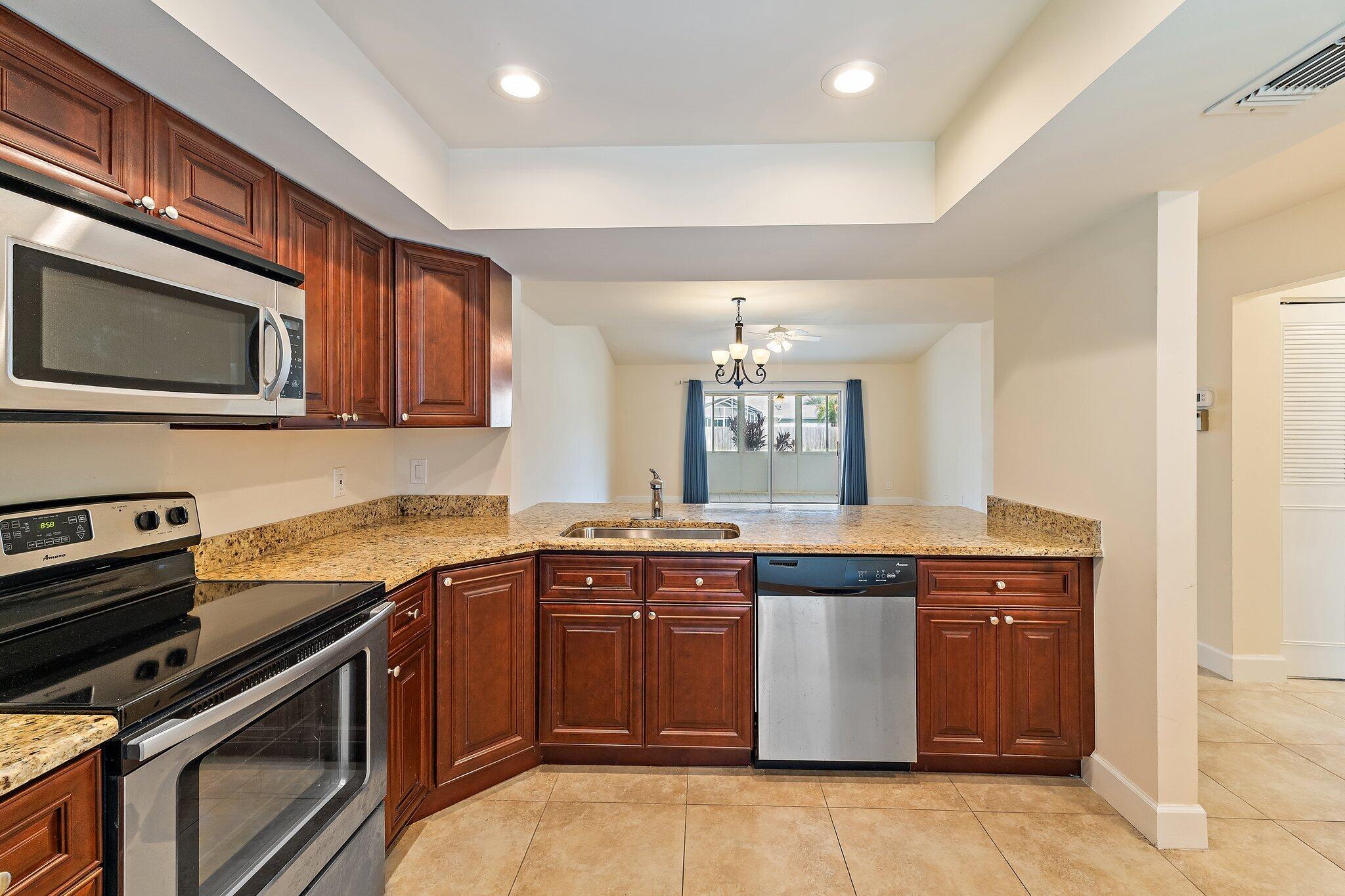 109 Doe Trail Jupiter, FL 33458 - Photo 6 of 26 a kitchen with stainless steel appliances granite countertop a stove a sink and a microwave